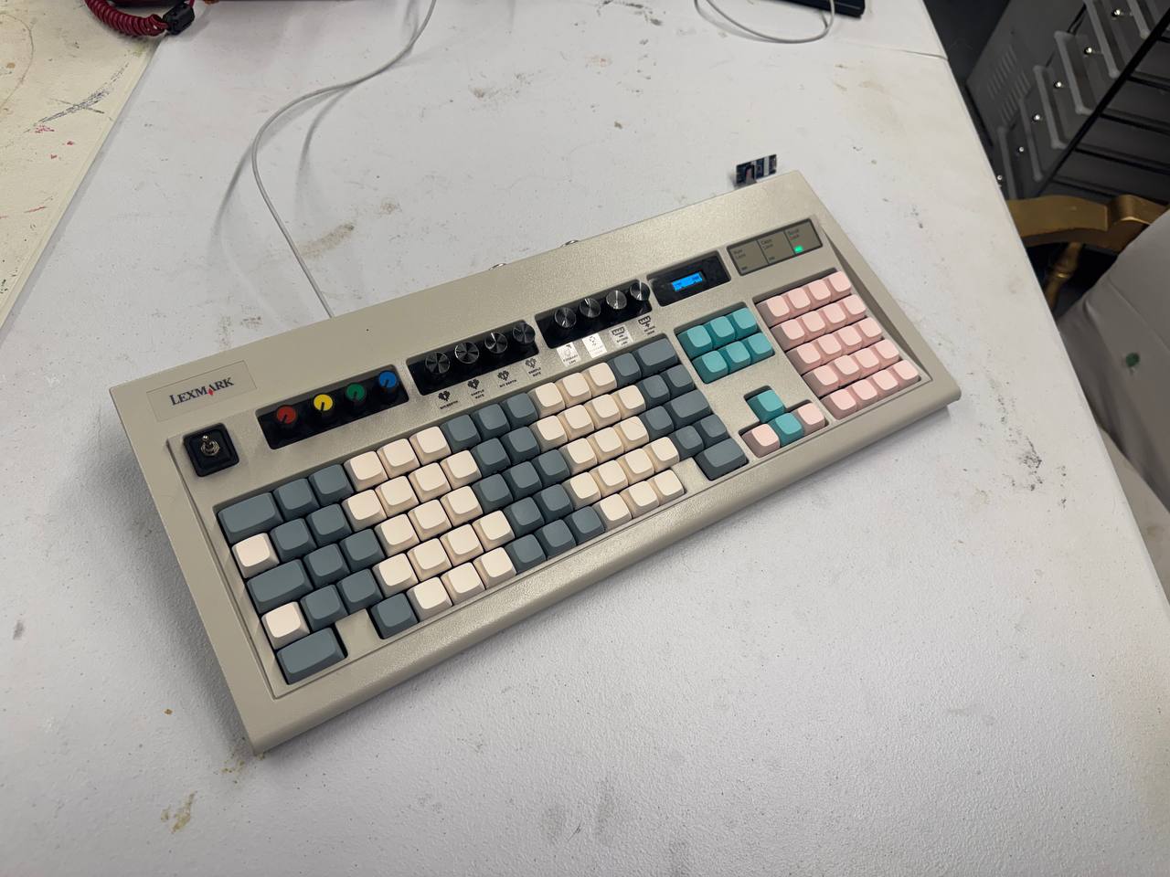 A beige computer keyboard rebuilt with colored musical keys, knobs, and an OLED